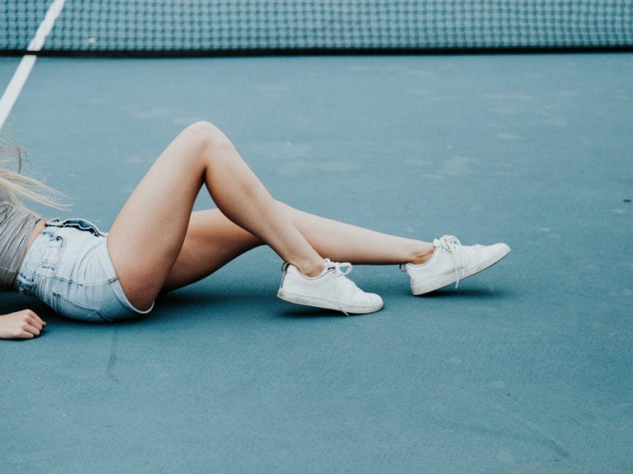 woman lying on tennis court floor during daytime