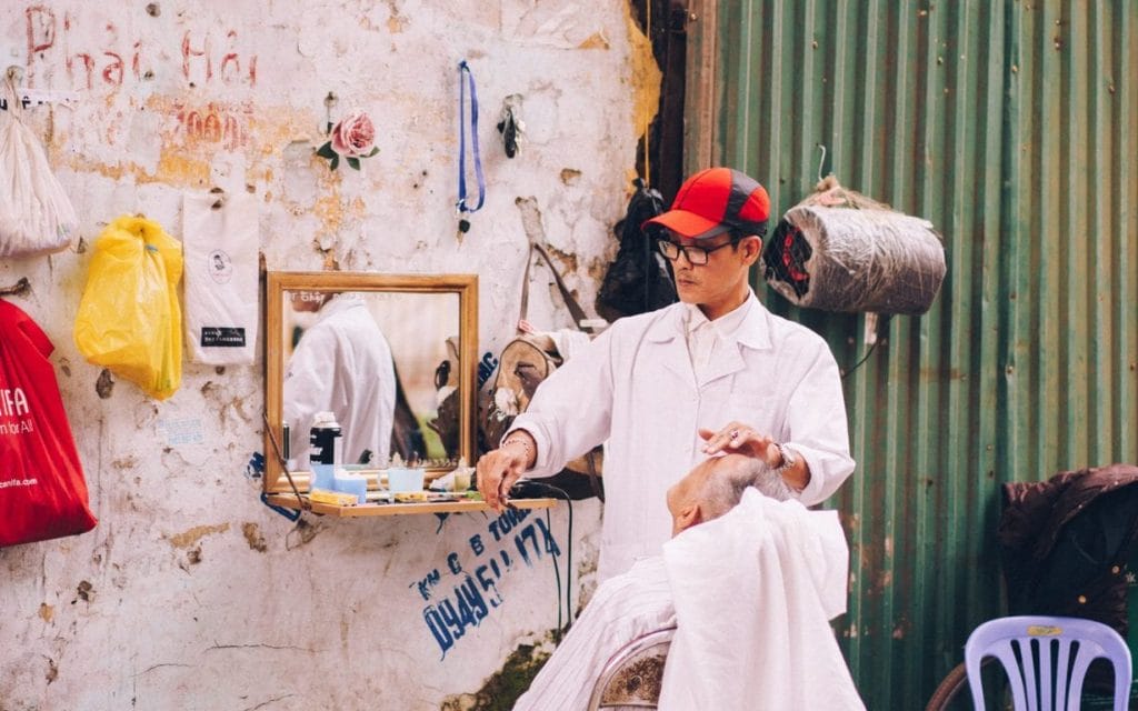 man in white shirt with red cap sits beside vanity mirror on wall