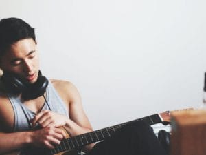 man holding guitar wearing headphones