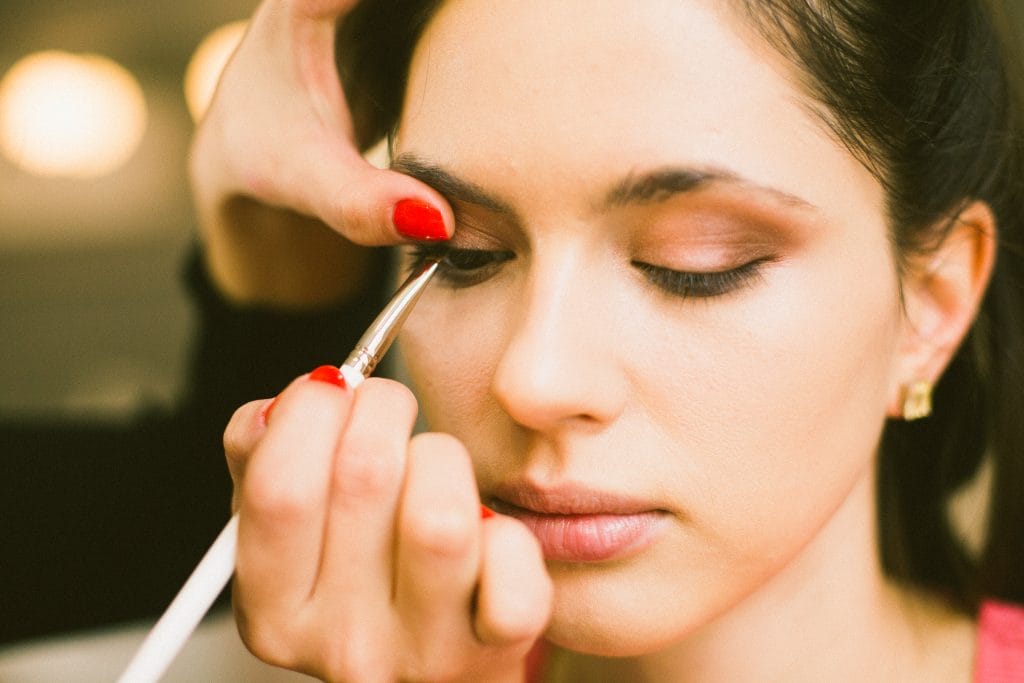 Crop stylist drawing eyeliner on model eyelid