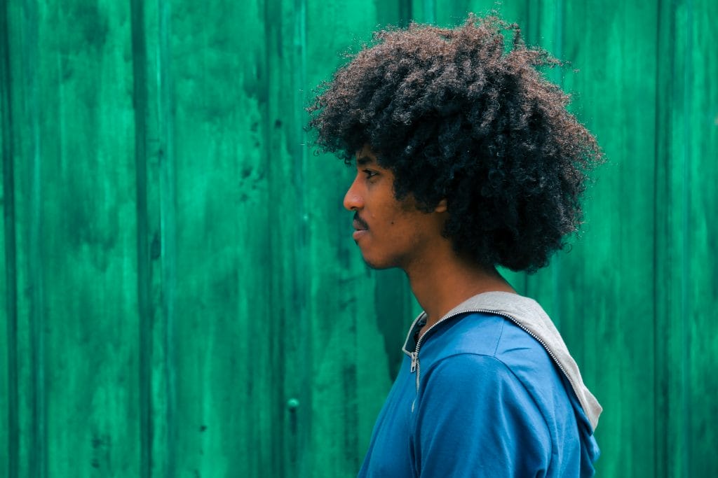 man facing right near green wall